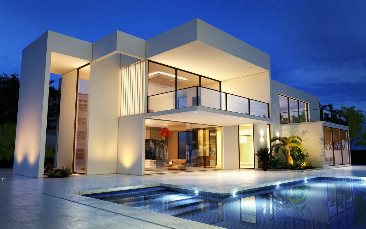 A modern white two-storey house at dusk, uplights washing its walls and a lit swimming pool in front of the glass doors